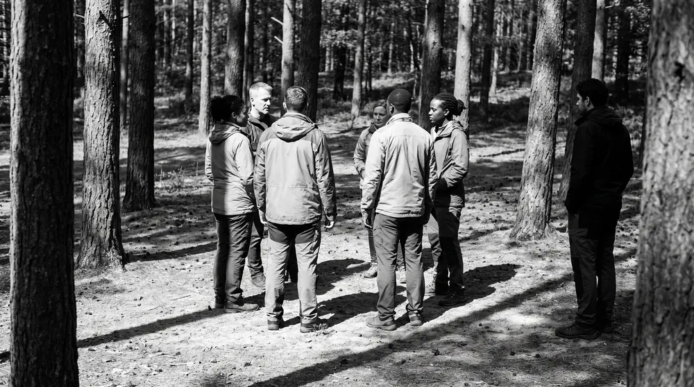 Een groep in een open plek, één persoon staat er net buiten